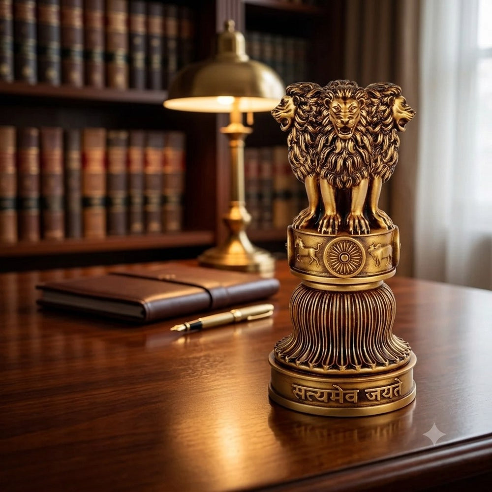 Ashok Stambh showpiece in antique gold on a polished wooden desk, beside a brass banker's lamp, a pen and a shelf of books