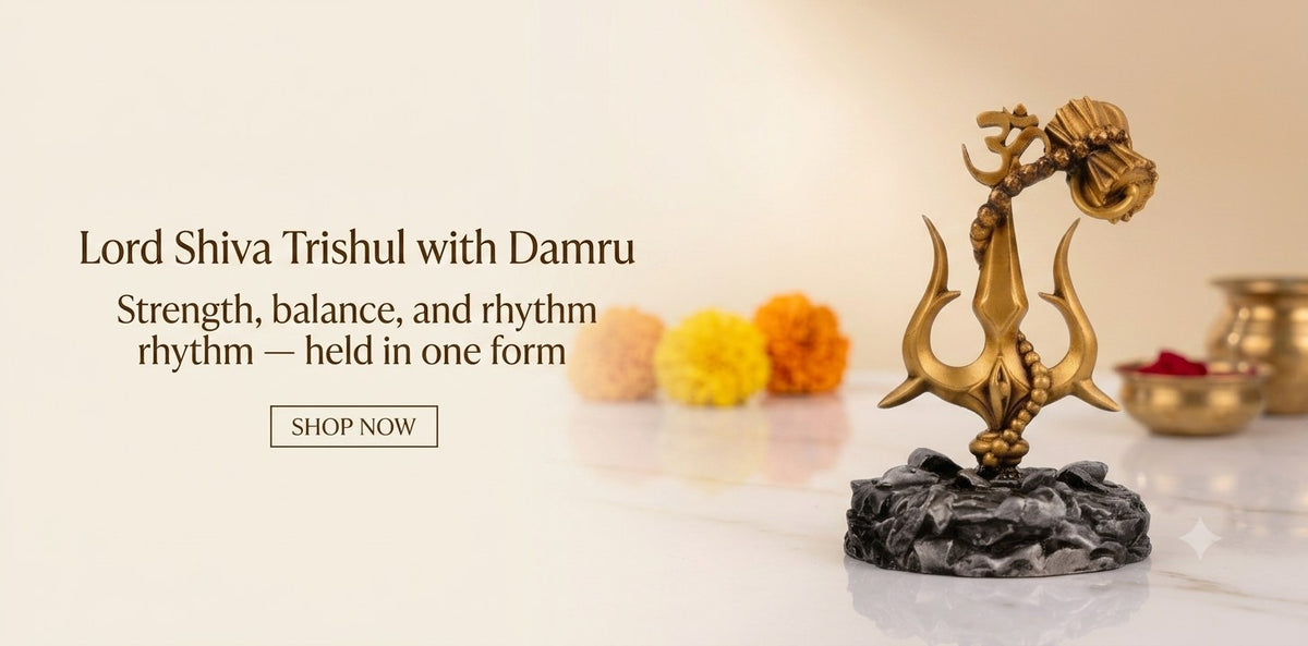 Lord Shiva trishul with damru in antique gold on a rock-effect base, with marigolds and a brass kalash